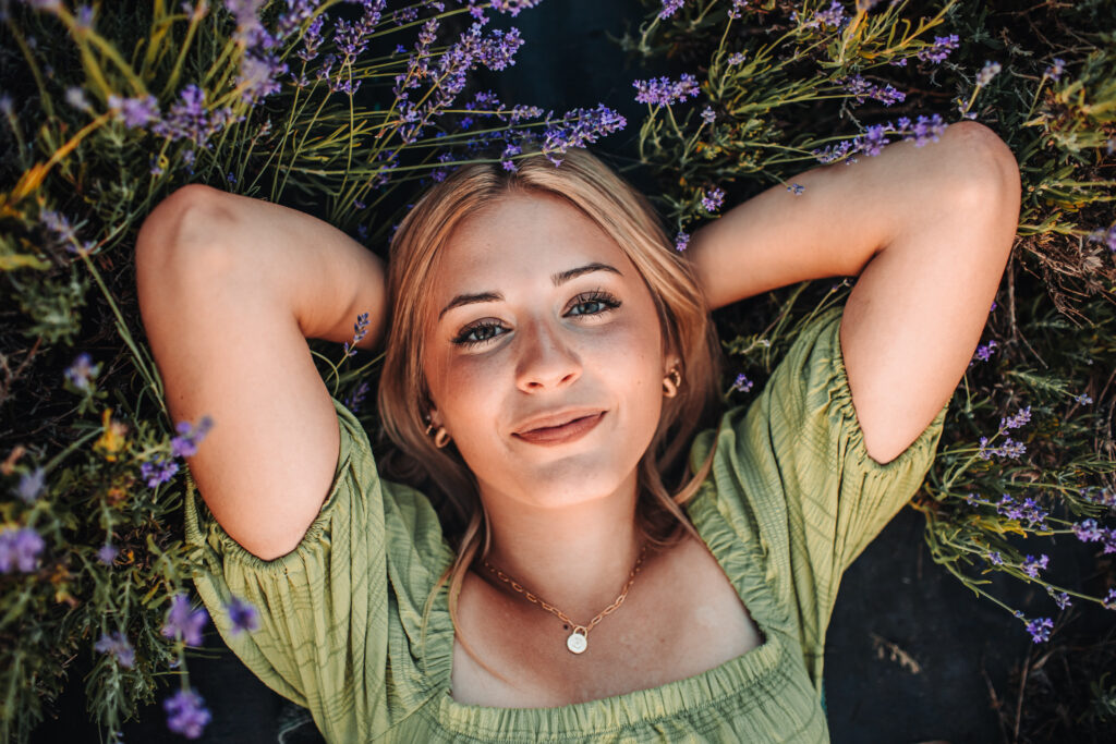 A high school senior laying in a lavender field during her senior photography experience.