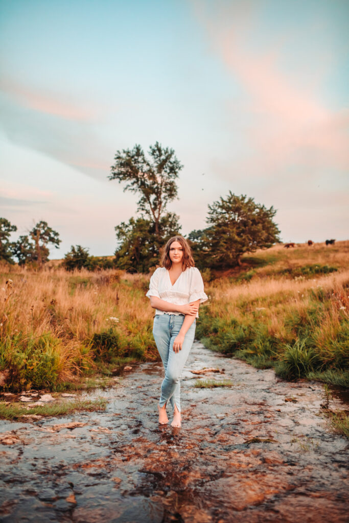 A high school senior standing in a creek during her senior photography experience.
