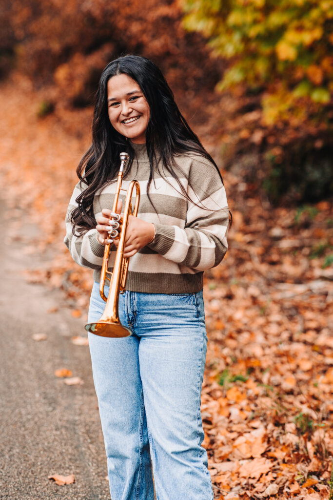 A high school senior standing with her trumpet during her senior photography experience.