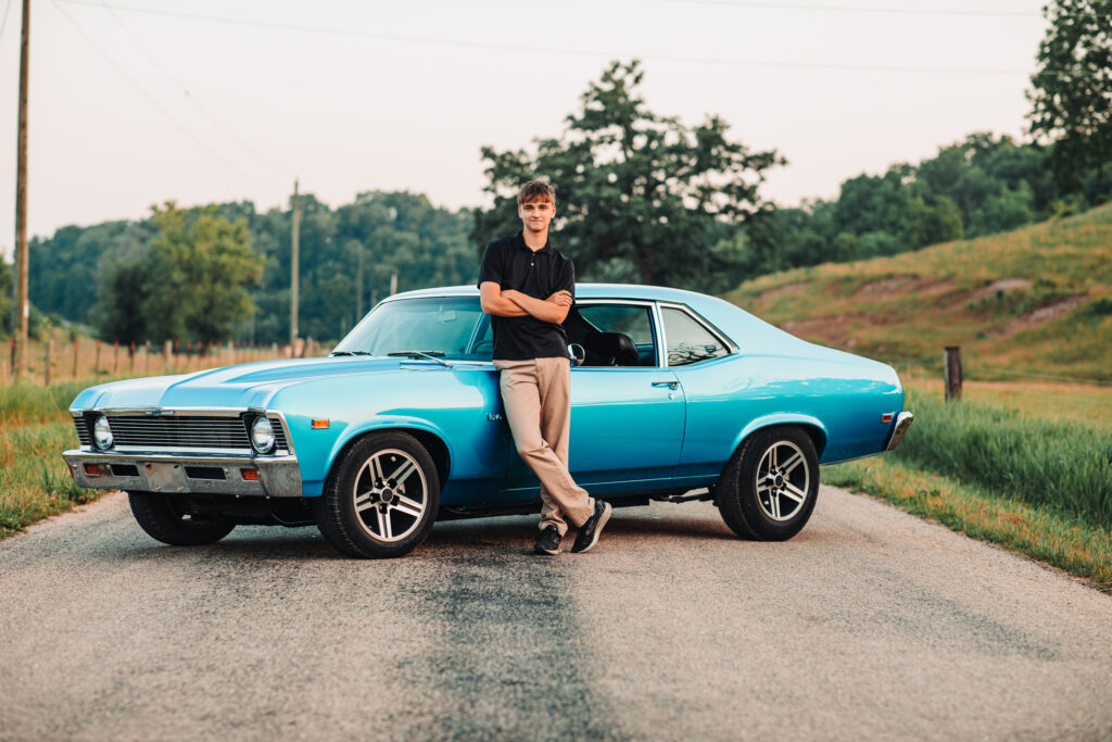 A high school senior standing next to his car during his senior photography experience.