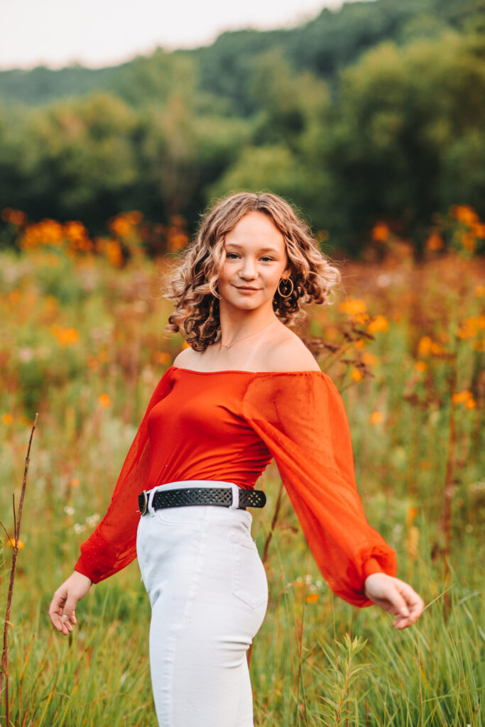 High school girl posing in a wild flower field during her senior session.
