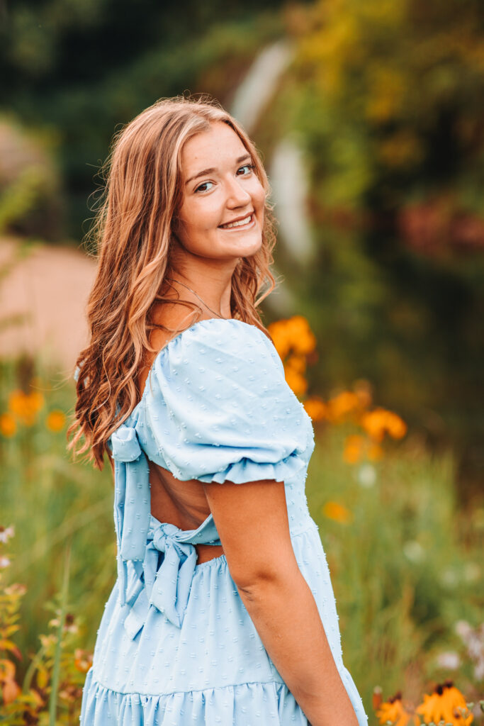 A high school senior standing in a wild flower field during her senior photography experience.