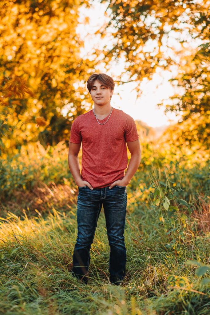 a high school senior posing in a rural grassy field.