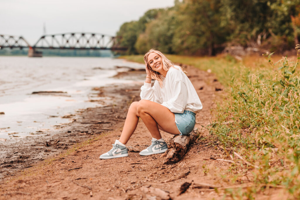 high school senior girl posing along side the shorelines of the mississippi river