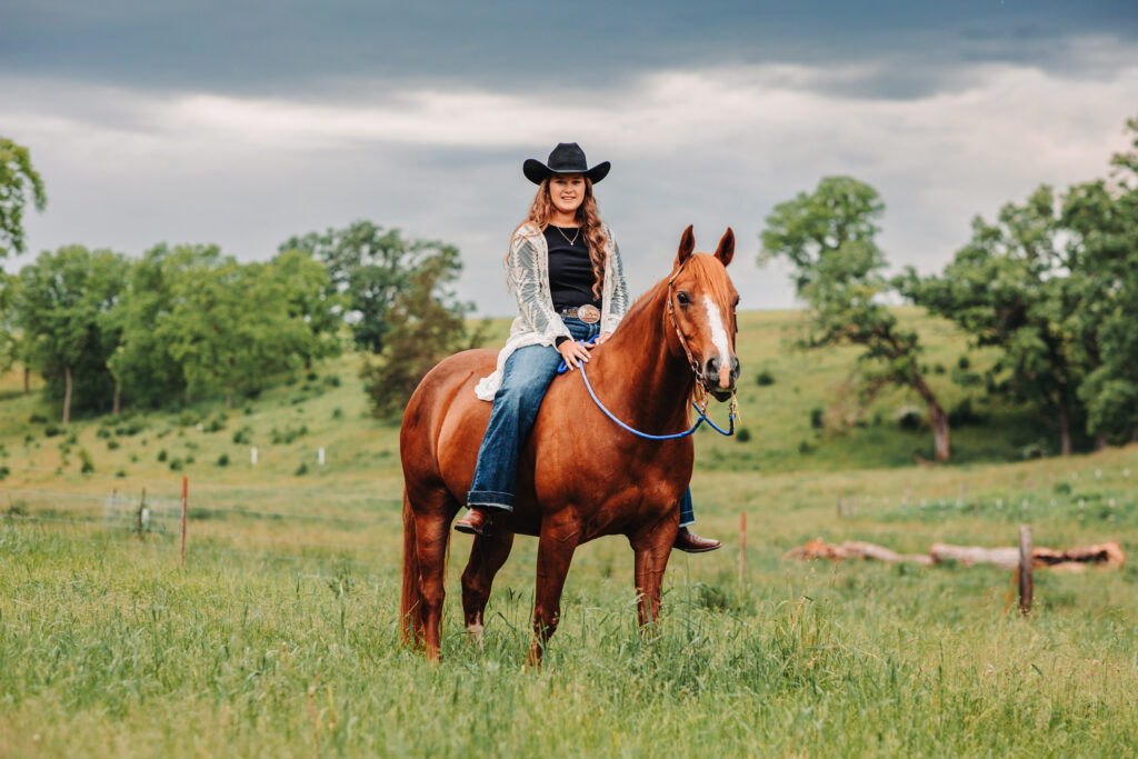 Megan with her five horses, all looking at the camera with a river bottom backdrop