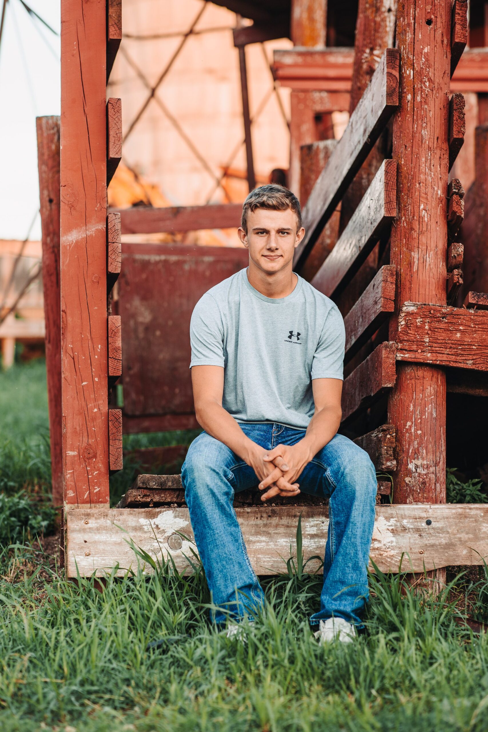 a high school senior guy sitting on a cattle chute on his family farm