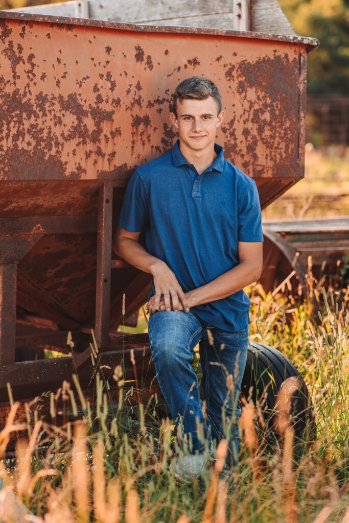 Levi standing against an old rustic gravity box on his family farm