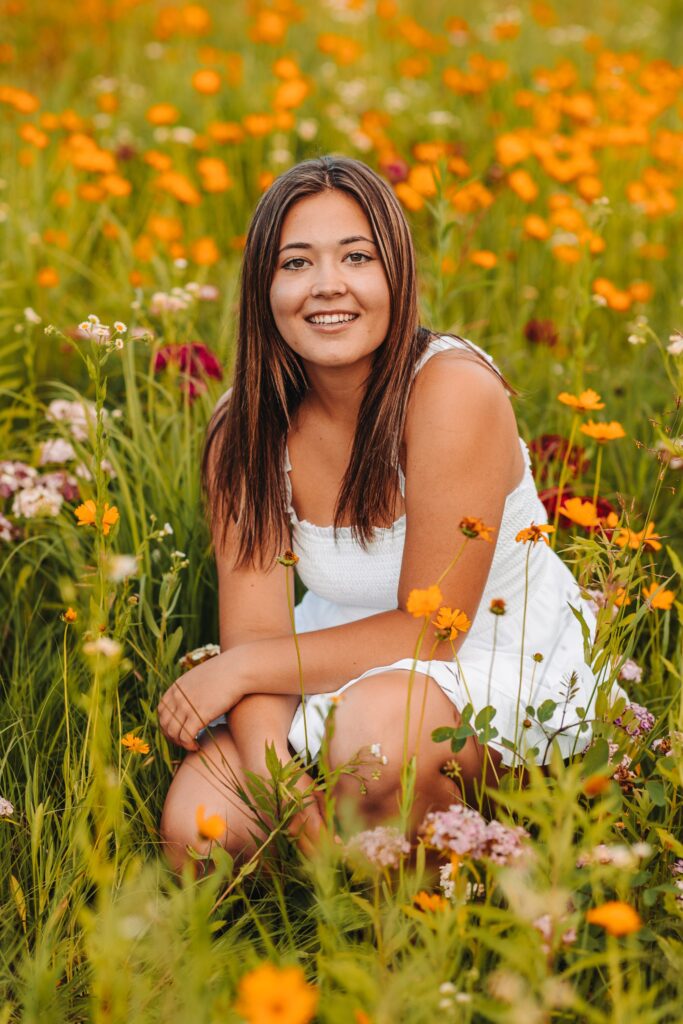 high school senior girl sitting in a flower field