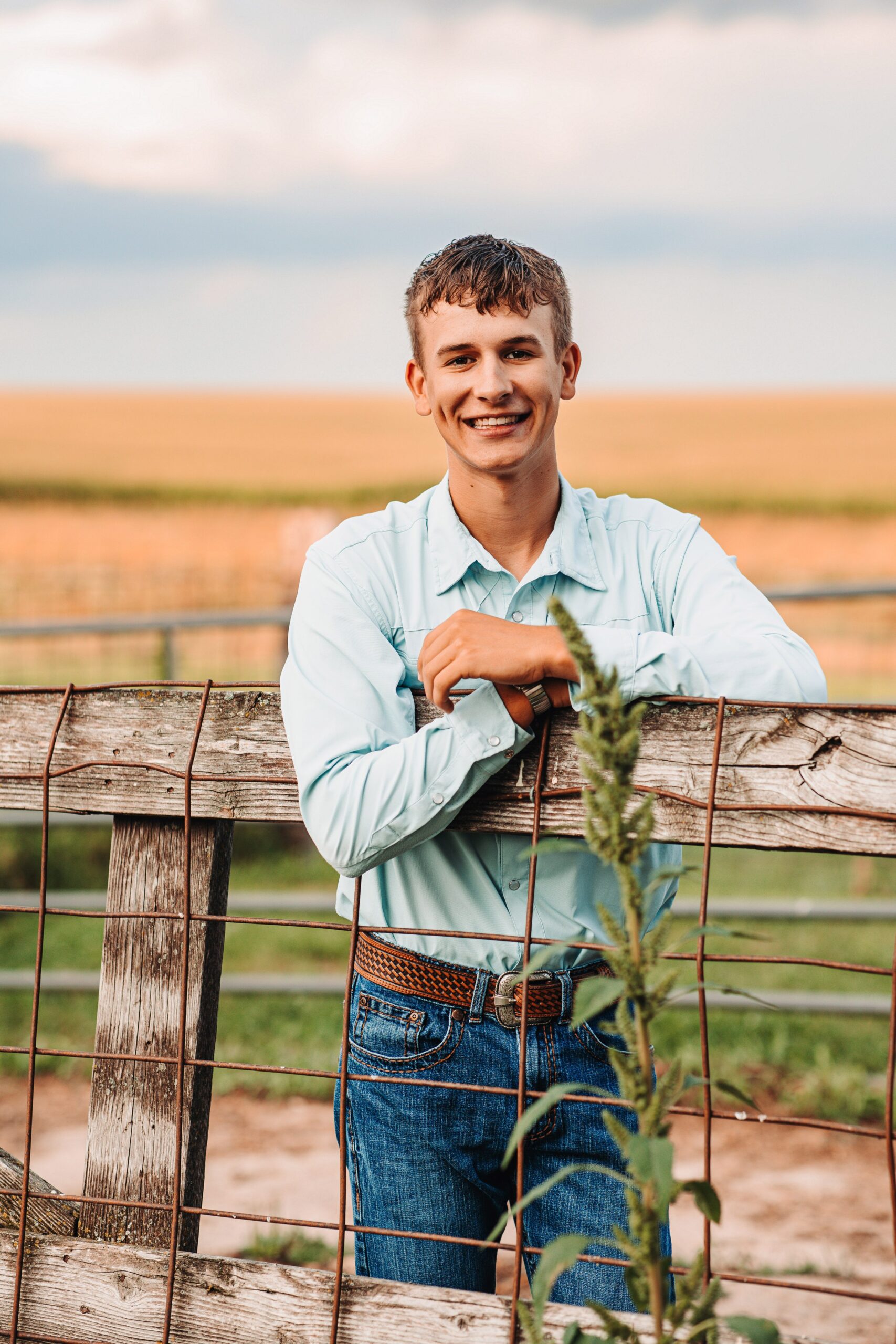 high school senior guy standing behind a wooden fence