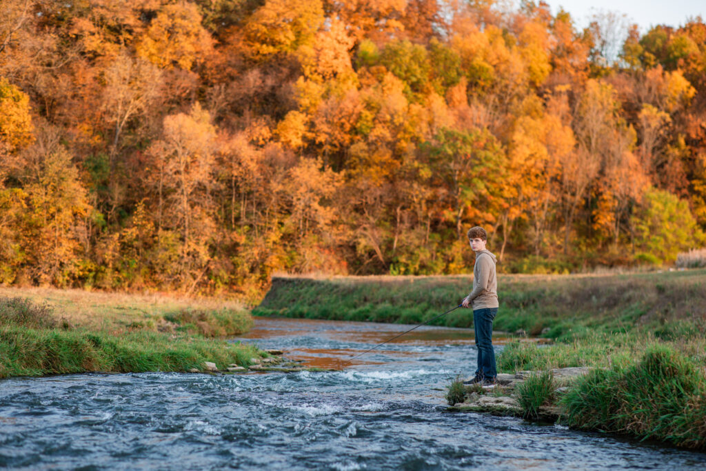 Senior boy fishing during his personalized photo session on a riverbank