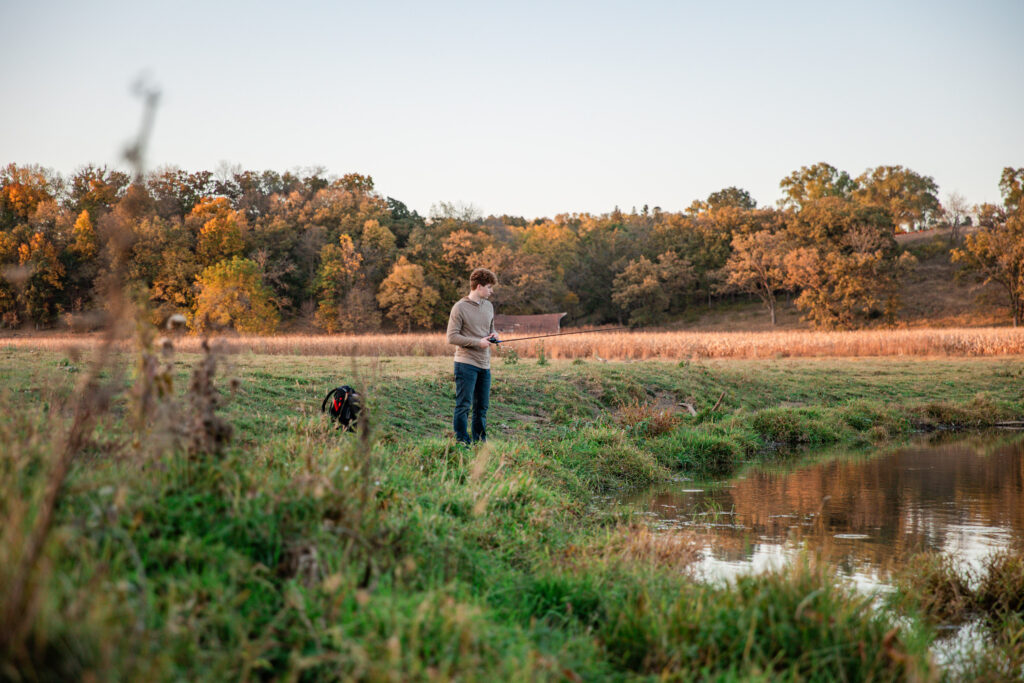 Senior boy fishing during his personalized photo session on a riverbank