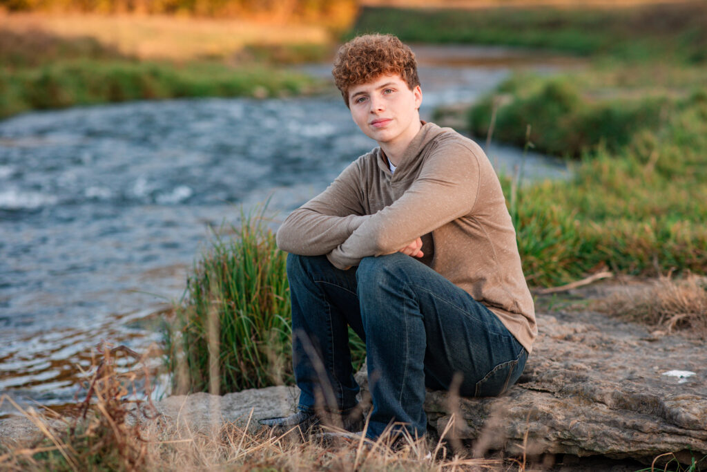 Senior boy fishing during his personalized photo session on a riverbank