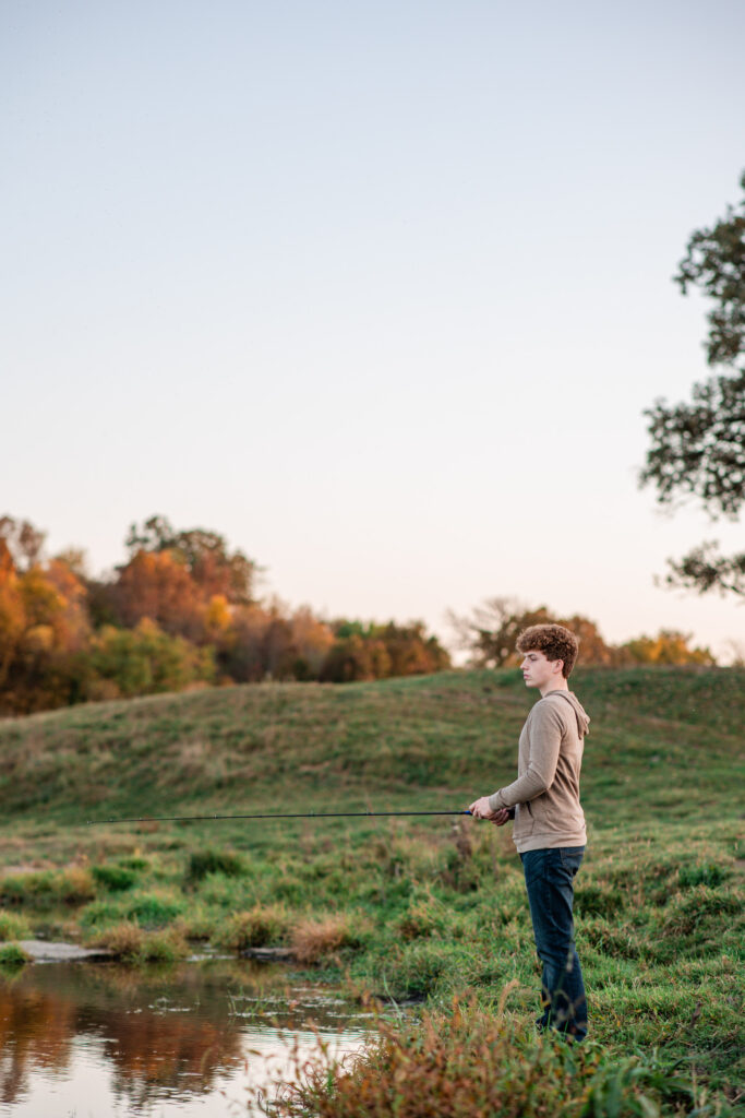 Senior boy fishing during his personalized photo session on a riverbank