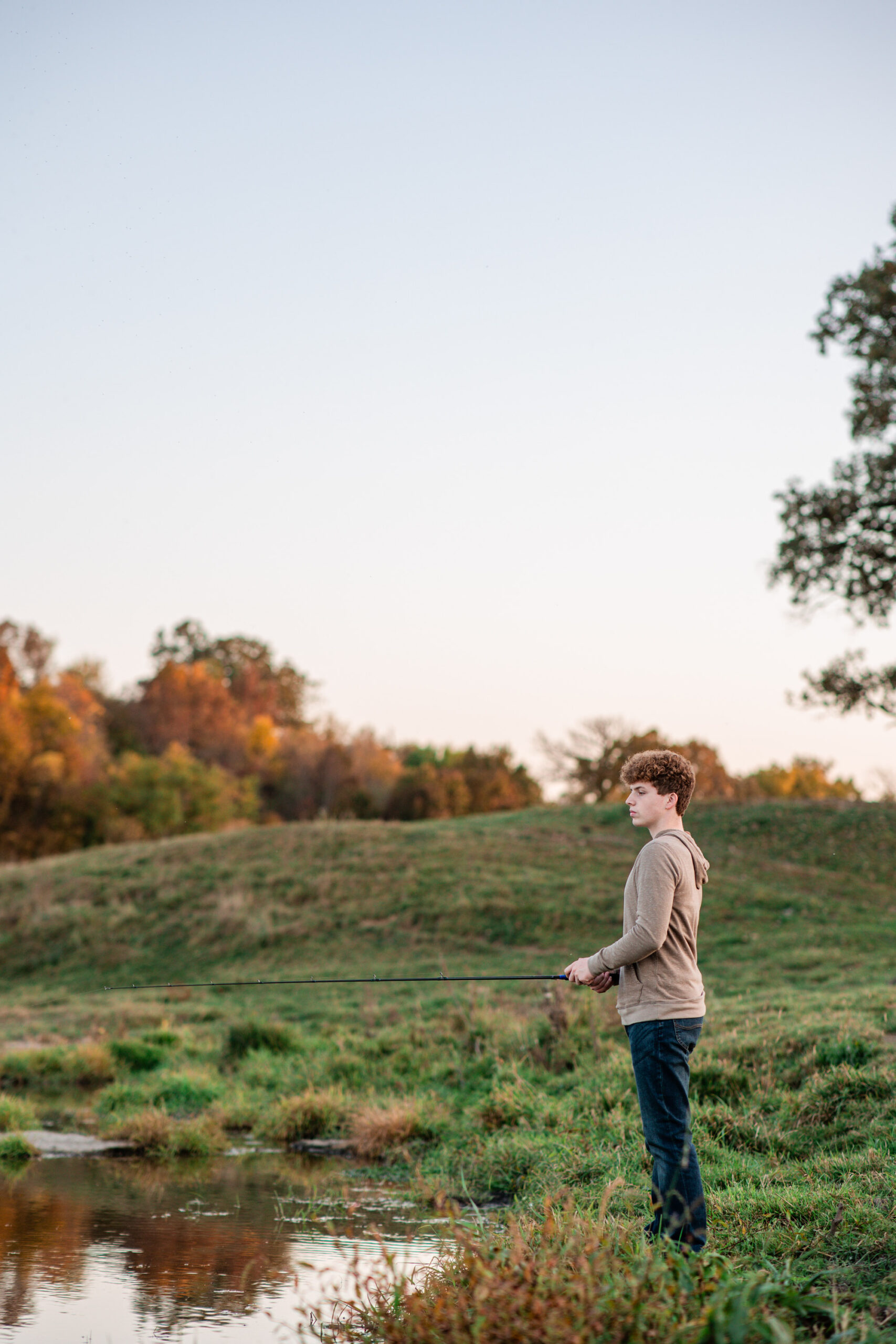 Senior boy fishing during his personalized photo session on a riverbank